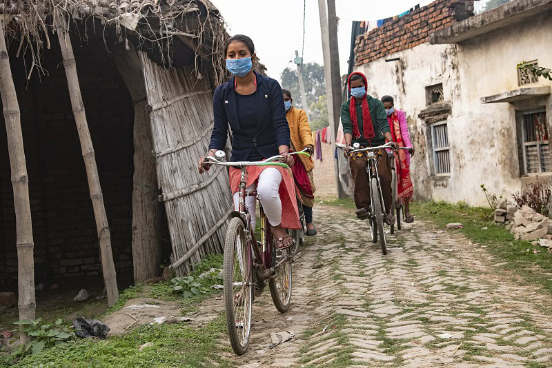 Girls who are creating community-centered solutions for improved health outcomes bicycle together in India. Credit: EngenderHealth