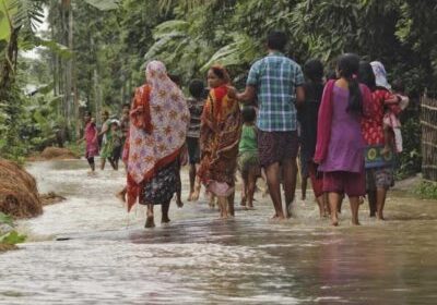 A woman (C) looks on as she walks with others to a safer place through a flooded road after incessant rains at Bullut village in Kamrup district in Assam, June 12, 2015. REUTERS/Stringer/Files